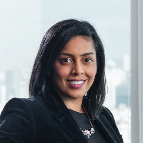 Person smiling in an office setting with a city view in the background.