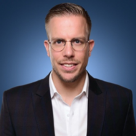 Man in a suit and glasses with a blue background.