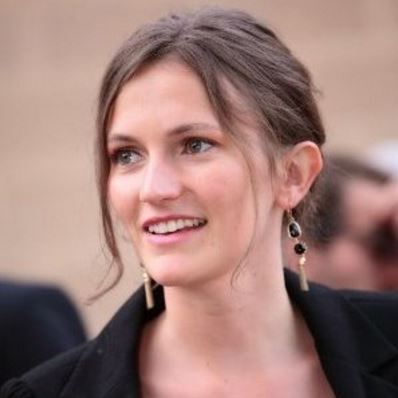 Smiling woman with long earrings and brown hair in an updo.