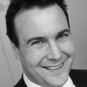 Black and white portrait of a smiling person in a suit.