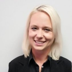 Person with short blonde hair smiling in a black jacket.
