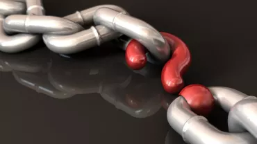 Close-up of a metallic chain with a red link standing out.