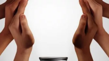 Several hands coming together to form a circular shape around a small bowl.