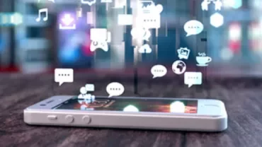 Smartphone with social media icons floating above its screen on a wooden table.
