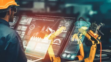 Engineer analyzing robotic arm data on a digital interface in a factory.