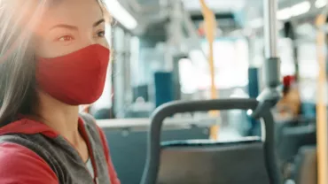 Woman wearing a red mask sitting on a bus