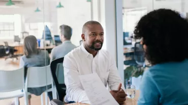 Two people having a conversation in a modern office setting.