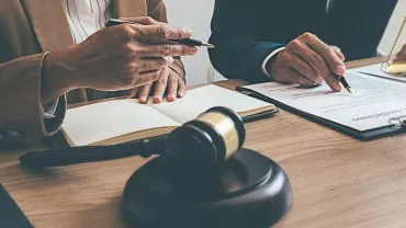 Two professionals discussing documents at a table with a gavel and scales.