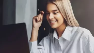 Woman smiling while looking at laptop screen.