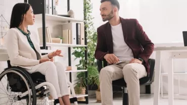 Two colleagues having a discussion in a modern office setting.
