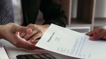Person handing over a resignation letter across a desk