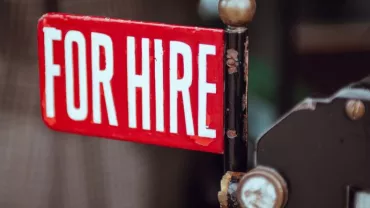 Close-up of a red 'For Hire' sign attached to a vintage taxi.