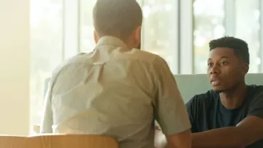 Two men sitting at a table engaged in a conversation.