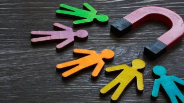 Colorful figures near a red magnet on a wooden table.