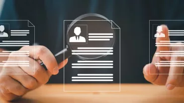 Person examining digital resumes with a magnifying glass.