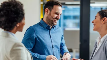 Three people having a cheerful conversation in an office setting.