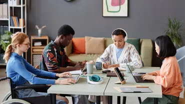 Diverse group of four people working together at a table in a modern office.