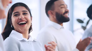 Group of people smiling and clapping in a bright room.