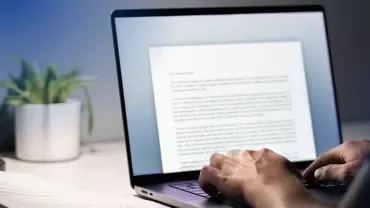A man typing a resignation letter on a laptop