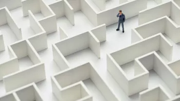 Businessman standing in a large maze, contemplating directions.