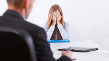 Woman sitting at a table with her head in her hands, looking stressed.