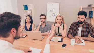 Group interview with four people listening to a speaker at a table.