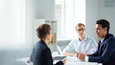 Three professionals having a meeting in a well-lit office room.