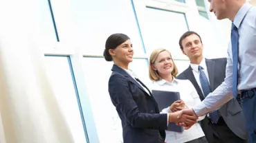 Business professionals shaking hands in a bright office setting.
