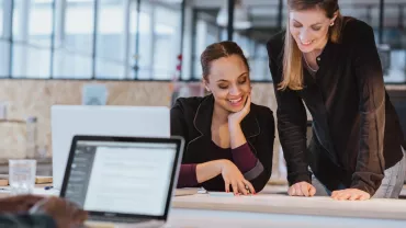 Two colleagues happily collaborating on a project in an office setting.