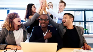 Group of colleagues celebrating with a high five in an office.