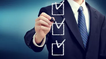 A man in a suit marking checkboxes on a transparent board.