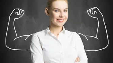 Smiling woman in white shirt with drawn strong arms on chalkboard background.