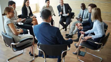 A group of business professionals in a meeting sitting in a circle.