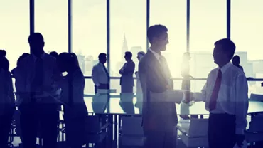 Silhouettes of business people interacting in a modern office setting.