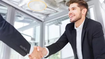 Smiling business professional shaking hands in an office setting.