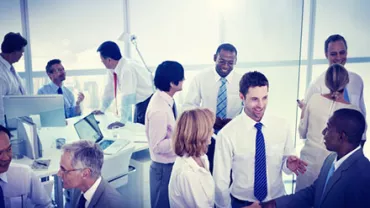 Group of colleagues in formal attire having a discussion in a bright office.