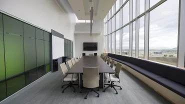 Modern conference room with a long table, chairs, and large windows.
