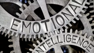 Close-up of metal cogs with 'Emotional Intelligence' engraved on them.