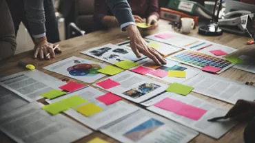 Team collaborating over documents and colorful sticky notes on a wooden table.