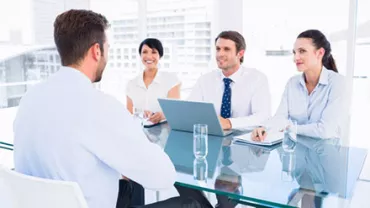 Group interview in modern office with four professionals discussing at a table.