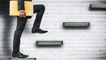 Businessman ascending steps with briefcase against a brick wall.
