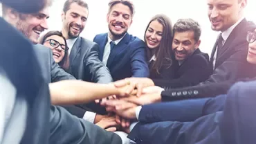 Group of business professionals stacking hands in teamwork.