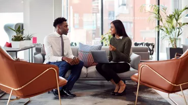 Two people having a discussion in a modern office lounge.