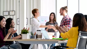 Group of coworkers celebrating a successful meeting with a handshake.