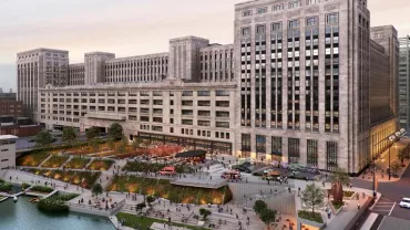 Historic postal building with a modern riverside park and urban activity.