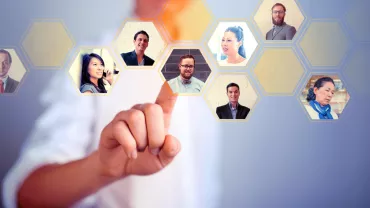 Person touching digital hexagonal interface with portraits.