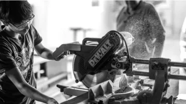 Person operating a circular saw wearing safety goggles.