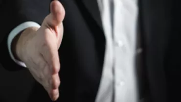 A person in a suit extending a handshake.