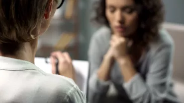 Two people in a discussion, one taking notes, the other listening attentively.