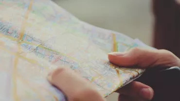 Person holding a folded map with various colorful street lines.